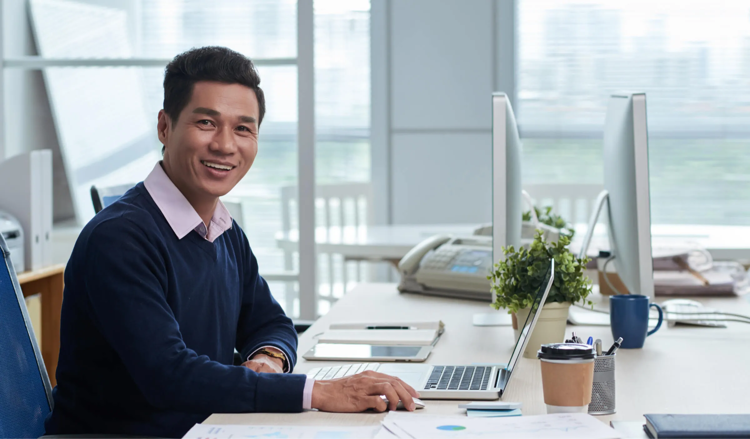 Man at office desk, smiling, symbolising a potential payment agent