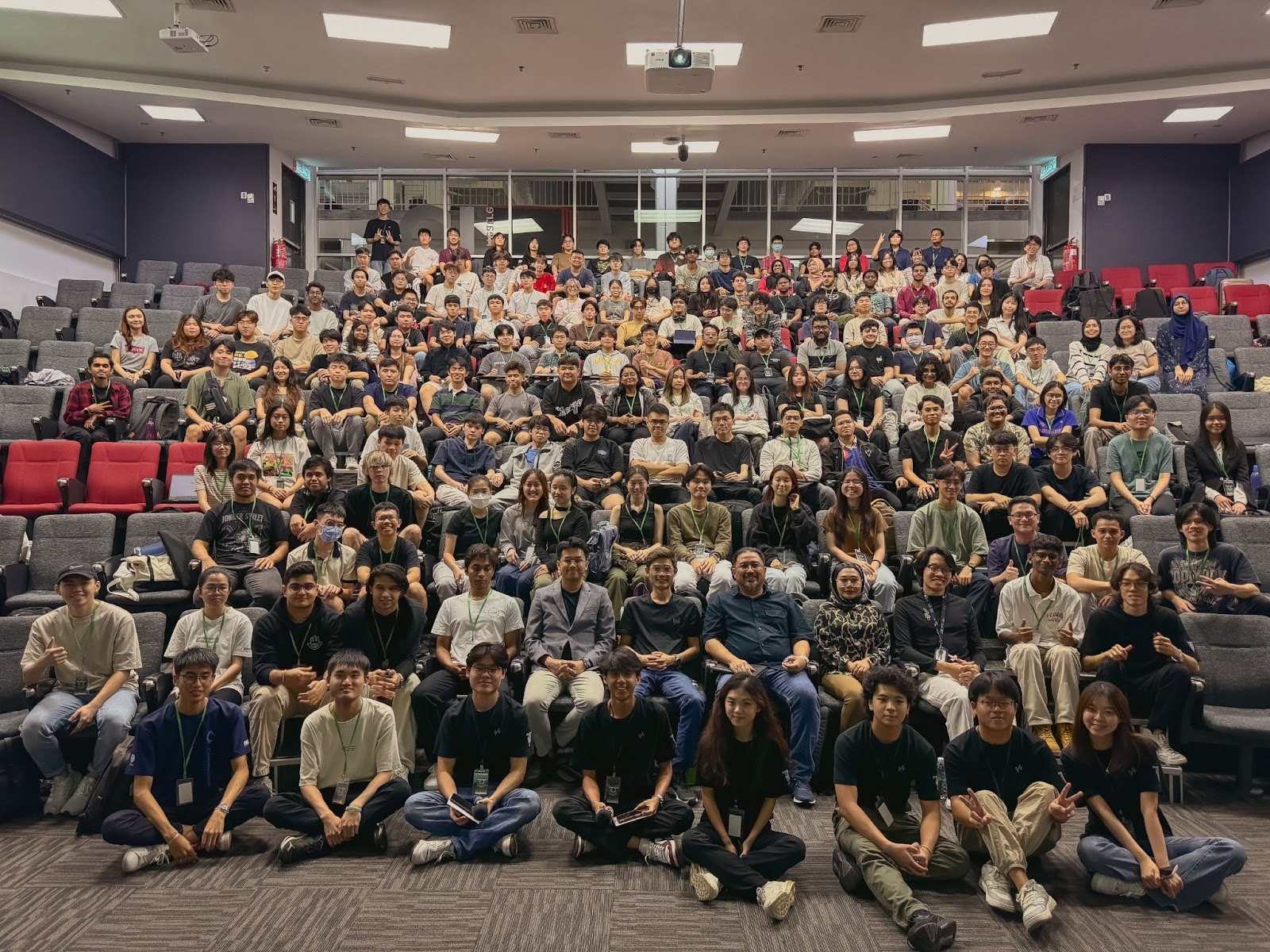 A group of happy hackathon attendees, including participants from Deriv, posing for a group photo in an auditorium
